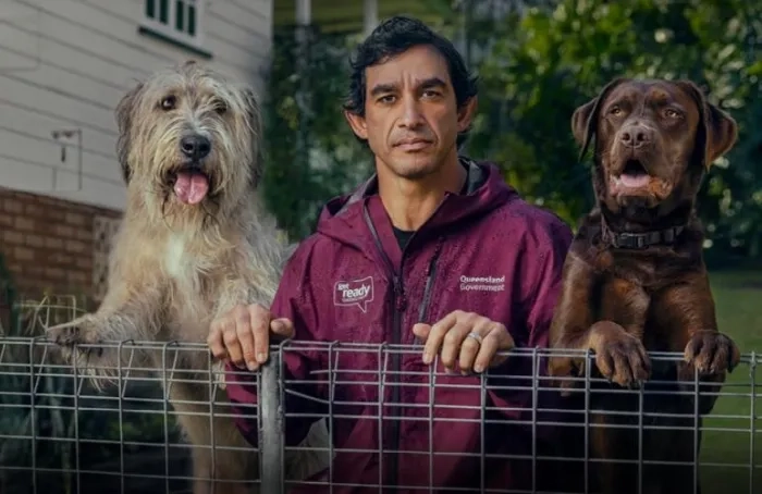 Johnathan Thurston leaning on a chain link fence with two dogs either side
